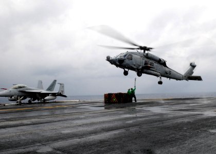 US Navy 110423-N-SG869-047 Logistics Specialist Seaman Immanuel Carter and Logistics Specialist 1st Class Kristopher Forest hook a load onto an SH