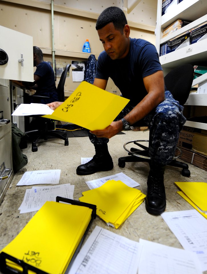 US Navy 110427-F-CF975-059 Logistics Specialist 2nd Class Juan Vasquez sorts supply orders to keep track of usage and items in demand aboard USNS C