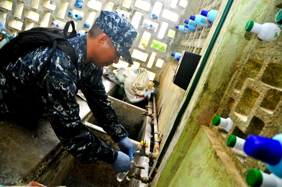 US Navy 110429-O-ZZ999-004 Hospital Corpsman 1st Class Van Manlambus takes a water sample from a hospital water supply before the opening of the ma
