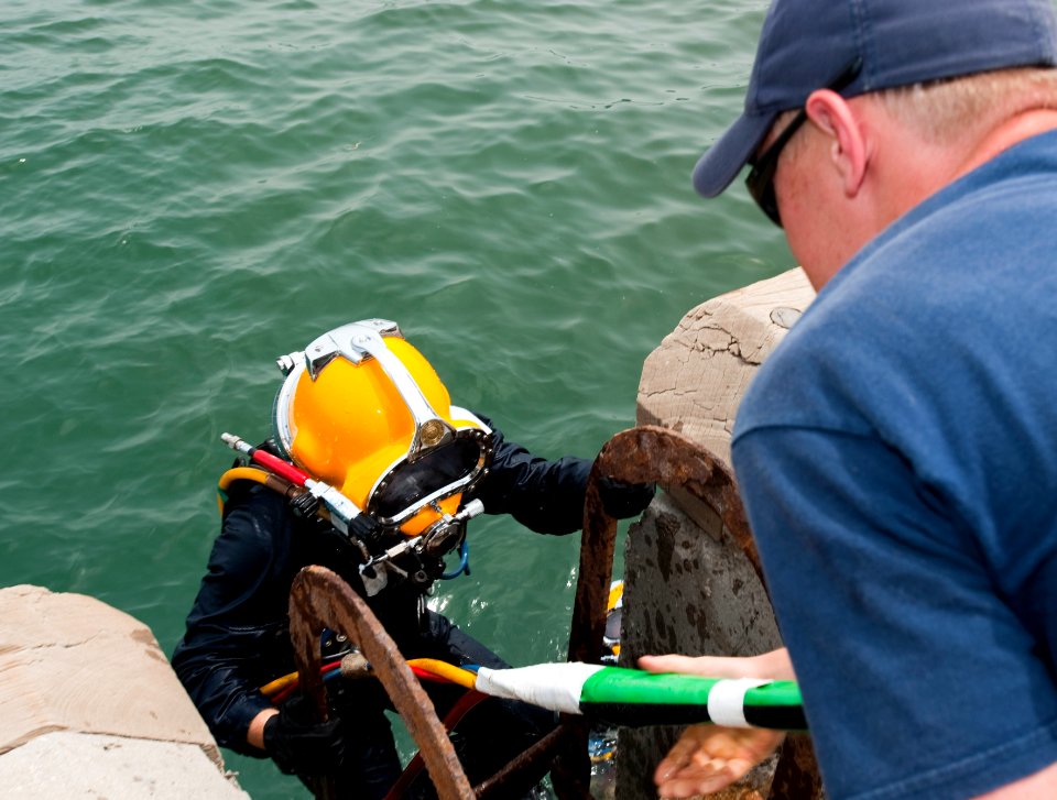 US Navy 110426-N-OT964-245 Navy Diver 1st Class Joel Sharp assists Navy Diver 2nd Class Cody Creger out of the water after completing a surface-sup