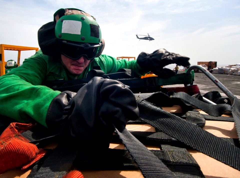US Navy 110428-N-DR144-468 Logistics Specialist Seaman Michael Richardson removes cargo netting from stores received during a vertical replenishmen