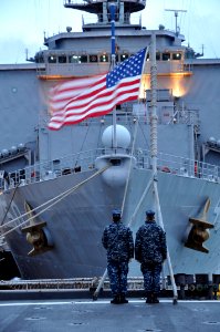 US Navy 110502-N-7293M-101 Boatswain's Mate 2nd Class Jonathan Bryant and Seaman Andrew Myers prepare to lower the national ensign during evening c