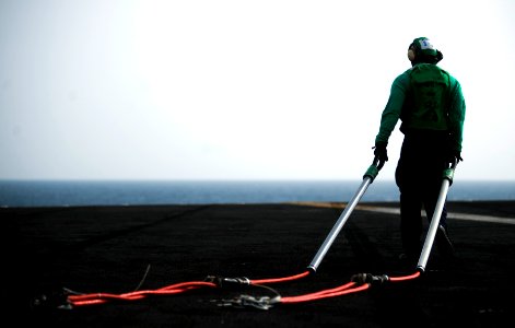 US Navy 110428-N-2055M-155 Logistics Specialist 2nd Class Omarge McDonald pulls cargo pennants across the flight deck during a vertical replenishme