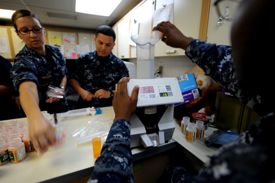 US Navy 110429-F-NJ219-015 Lt. Laura Modafferi, from New Hope, Pa., collects completed medicine bags as Hospital Corpsman 2nd Class Jorge Nunez