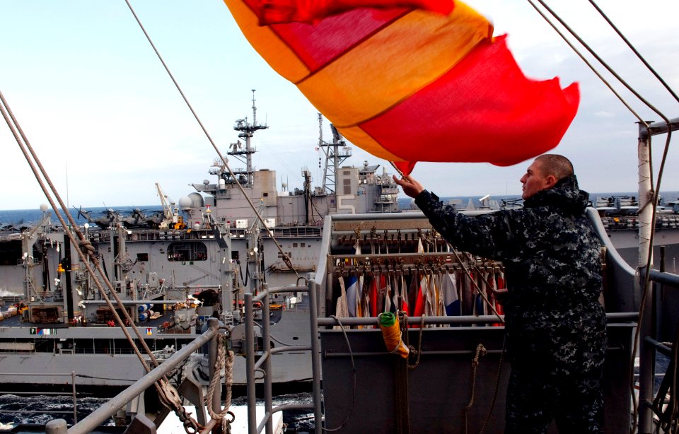 US Navy 110425-N-QP268-032 Quartermaster Seaman Christopher Koch hoists the Romeo flag aboard the amphibious dock landing ship USS Whidbey Island (