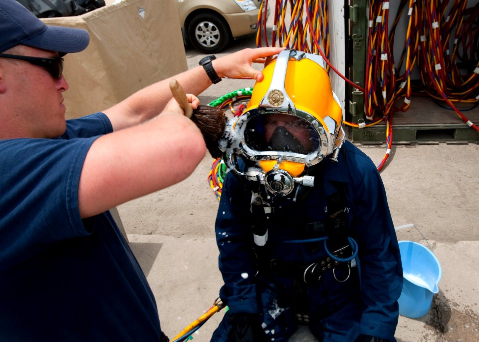 US Navy 110426-N-OT964-167 Navy Diver 1st Class Joel Sharp uses soapy water to check for air leaks on the Kirby Morgan 37 diving helmet of Navy Div