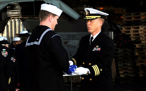 US Navy 110502-N-OI955-154 Cmdr. Stevin Johnson passes the flag to Religious Programs Specialist 3rd Class Daniel Graham during a burial at sea cer