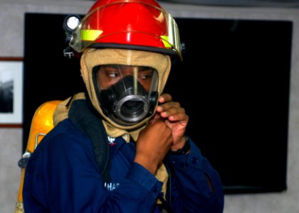 US Navy 110429-N-MM360-048 Ship's Serviceman 3rd Class Gregory Charles dons firefighting gear during a general quarters drill aboard the guided-mis
