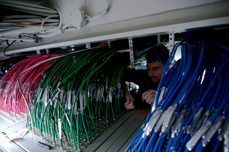 US Navy 110430-N-8040H-142 nterior Communications Electrician 3rd Class Michael Love performs maintenance on RGB cables in the secure video distrib