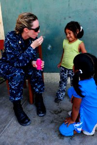 US Navy 110506-F-NJ219-067 Lt. Cmdr. Michelle Carr blows bubbles for Peruvian children as they wait at a medical site during Continuing Promise 201 photo