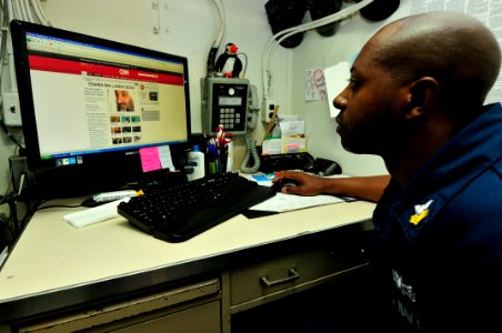 US Navy 110502-N-XO436-001 Master-at-Arms 1st Class Kelvin Lee reads about Osama Bin Laden's death while reading the morning news aboard the guided