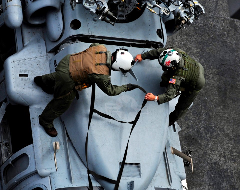 US Navy 110511-N-OI955-141 Lt. j.g. Jeremy Hans and Lt. Cmdr. Joseph Cortopassi adjust straps on an MH-60S Sea hawk helicopter