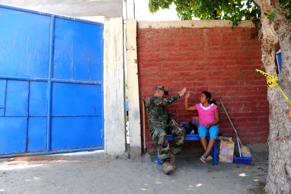 US Navy 110508-F-ET173-275 Construction Electrician 1st Class Rex Miller high fives a Peruvian child outside of a school building during Continuing