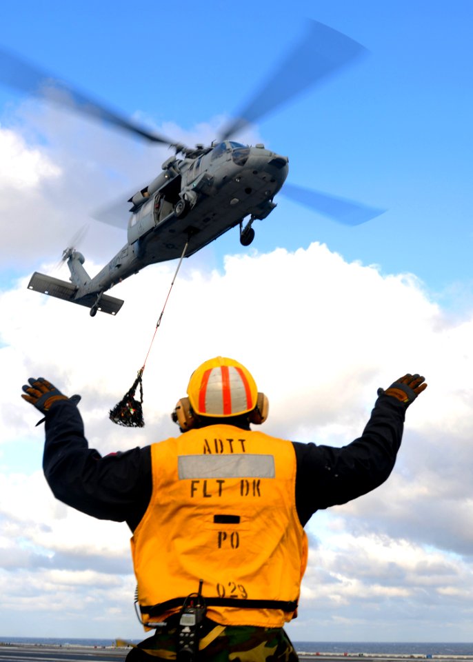 US Navy 110512-N-QL471-061 A Sailor signals to an MH-60S Sea Hawk helicopter during a vertical replenishment aboard USS George H.W. Bush (CVN 77)