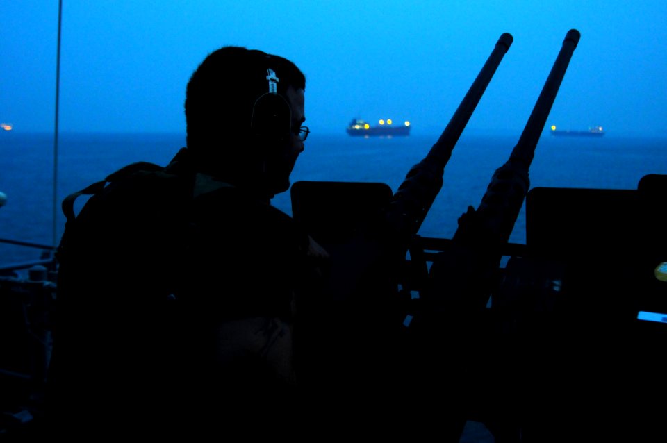 US Navy 110513-N-SP676-047 Mineman Seaman John Allison stands watch on a twin-mounted .50-caliber machine gun station aboard the mine countermeasur