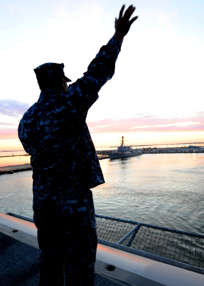 US Navy 110511-N-XE109-090 Aviation Boatswain's Mate (Fuel) 2nd Class Andy Nunez waves to family and friends on the pier of Naval Station Norfolk