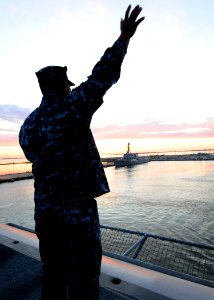 US Navy 110511-N-XE109-090 Aviation Boatswain's Mate (Fuel) 2nd Class Andy Nunez waves to family and friends on the pier of Naval Station Norfolk
