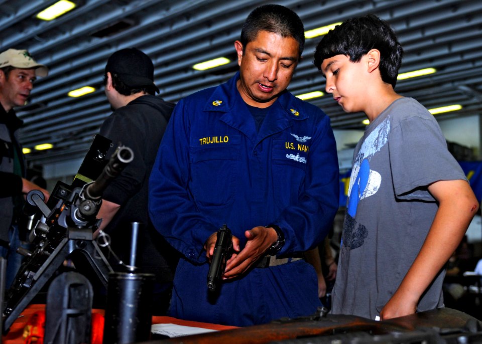 US Navy 110515-N-3154P-239 Chief Aviation Machinist's Mate Emilio Trujillo explains firearm function and safety to his son during a Tiger Cruise ab