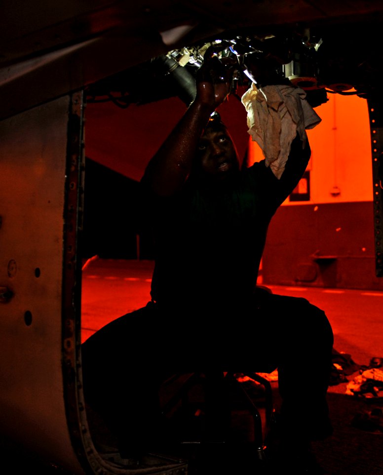 US Navy 110512-N-GC412-008 Aviation Machinist's Mate 3rd Class Olamide Osude epairs an afterburner control on an F-A-18C Hornet aboard USS John C