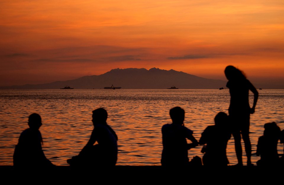 US Navy 110516-N-DR144-408 Manila residents watch the sunset from a sea wall while the Nimitz-class aircraft carrier USS Carl Vinson (CVN 70) and t