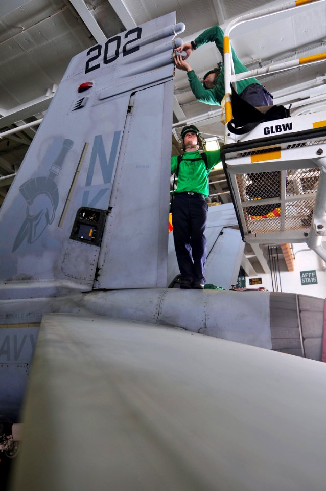US Navy 110514-N-1004S-108 Sailors install an antenna onto the left vertical stabilizer of an F-A-18E Super Hornet