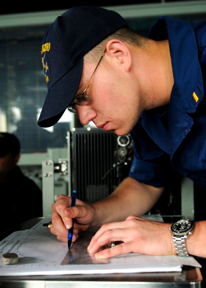 US Navy 110515-N-YM590-086 Ensign Austin E. Ayres plots the ship's position on a maneuvering board on the bridge of the guided-missile cruiser USS