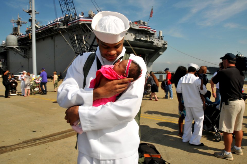 US Navy 110516-N-QY430-138 Machinist's Mate Fireman Demontay Blue holds his daughter for the first time during a homecoming celebration for the amp