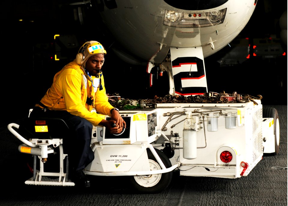 US Navy 110515-N-YC050-039 Aviation Boatswain's Mate (Handling) Airman Darrell Winston maneuvers an E-2C Hawkeye in the hangar bay aboard the aircr