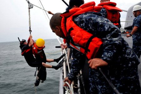 US Navy 110517-N-WW409-379 Search and rescue swimmer Seaman Matthew Honan is raised out of the water with Oscar during a man overboard drill aboard