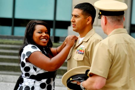 US Navy 110519-N-ZB612-116 Chief Construction Electrician Leonardo Calderon has his chief's anchors pinned by his wife, Jamiah, during his meritori