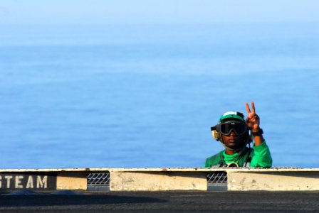 US Navy 110518-N-SB672-137 Aviation Boatswain's Mate (Equipment) Airman Aaron Jones signals to a shooter from the deck edge operator station on the