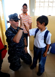 US Navy 110524-N-NY820-312 Cmdr. Mark Stewart gets a high-five during a Give A Kid A Backpack community service event at a school in Manta, Ecuador photo
