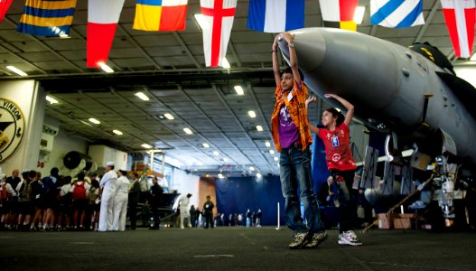 US Navy 110525-N-TU221-593 Children play on the nose of an F-A-18C Hornet during a tour in the hangar bay of the Nimitz-class aircraft carrier USS