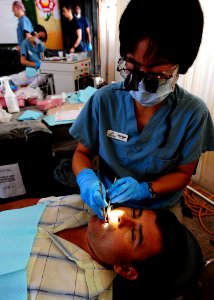 US Navy 110523-N-QD416-309 Dr. Sussi Yamaguchi performs minor dental repair on a patient's teeth at a clinic near Manta, Ecuador, during Continuing photo