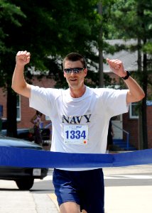 US Navy 110526-N-5292M-014 Lt. Cmdr. Jonathan Hughes, assigned to Commander, Navy Reserve Forces Command, crosses the finish line during the Memori