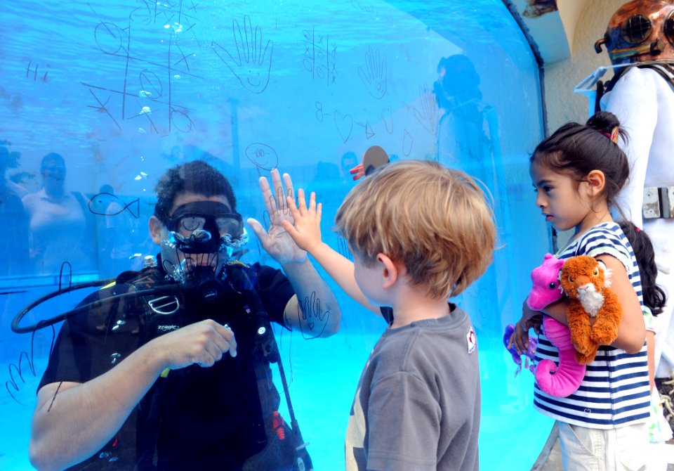 US Navy 110528-N-GO025-189 Navy Diver 1st Class Michael Patterson high-fives a boy through the aquarium glass during a Navy diver demonstration at