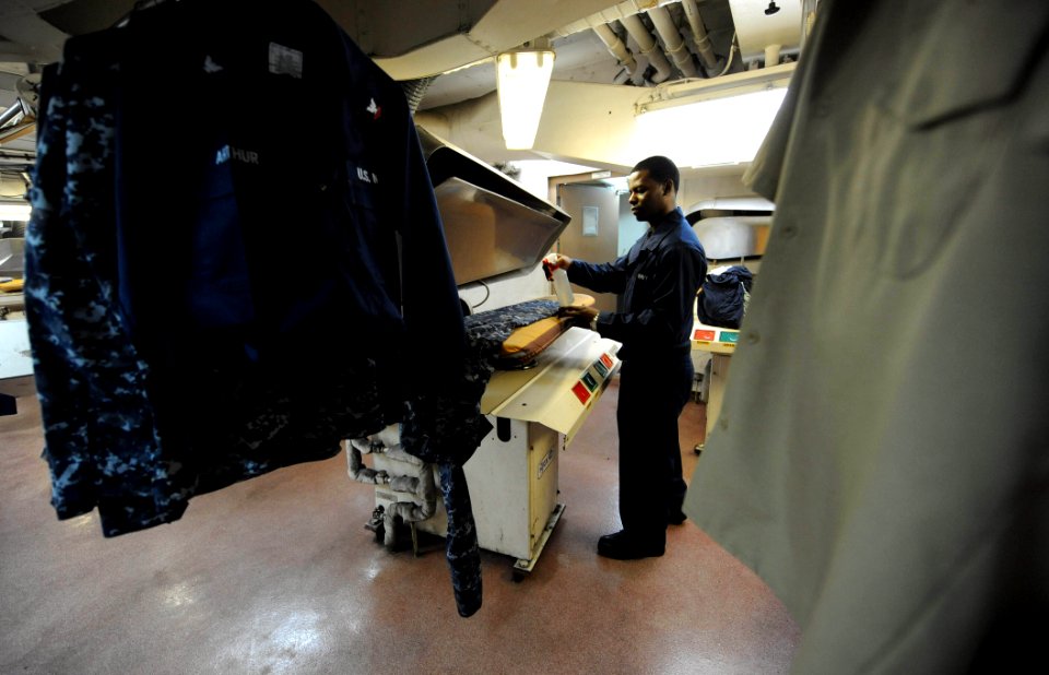 US Navy 110601-F-ET173-118 Ship's Serviceman Seaman Ryan Swinton presses uniforms in the ship's laundry room aboard USNS Comfort (T-AH 20) during C