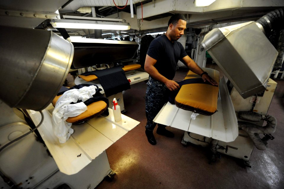 US Navy 110601-F-ET173-087 Ship's Serviceman 2nd Class Jerome Lewis-Tinsley presses uniforms in the ship's laundry room aboard USNS Comfort (T-AH 2
