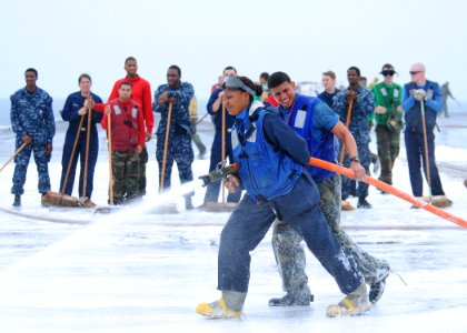 US Navy 110605-N-DS193-021 Sailors spray down the flight deck of the aircraft carrier USS George Washington (CVN 73) with aqueous film forming foam