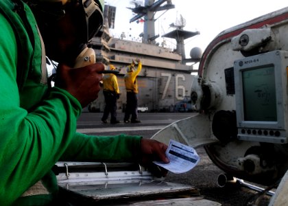 US Navy 110605-N-SB672-050 Aviation Boatswain's Mate (Equipment) Airman Aaron Jones uses the sound-powered telephone in the center-deck hatch to re