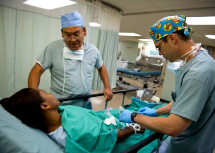 US Navy 110605-N-RM525-024 Osvaldo Romero, left, from Latter-Day Saints Charities, talks to a patient while Lt. Cmdr. James Solomon, a Navy anesthe