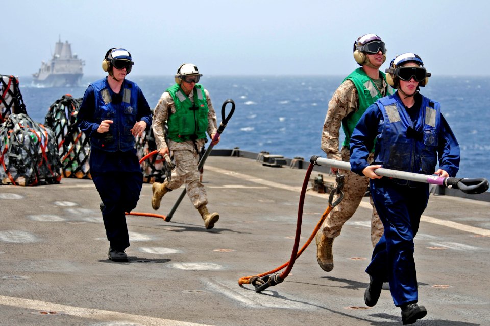 US Navy 110607-N-RC734-172 Sailors run to clear cargo pendants from the flight deck aboard USS Comstock (LSD 45) during a vertical replenishment