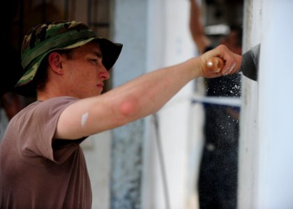US Navy 110604-N-QD416-273 Master-at-Arms 3rd Class Garry Clark, from Tampa, Fla., chips paint from the walls of the Institucion Ciudadela Educativ
