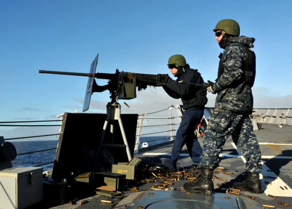 US Navy 110606-N-NL541-124 Logistics Specialist 3rd Class Mickey Thiele fires a .50 caliber machine gun while Seaman Michael Trusik maintains radio