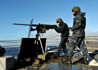 US Navy 110606-N-NL541-124 Logistics Specialist 3rd Class Mickey Thiele fires a .50 caliber machine gun while Seaman Michael Trusik maintains radio