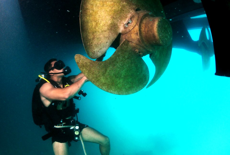 US Navy 110609-N-XD935-137 Navy Diver 3rd Class Bryan Myers, assigned to Mobile Diving and Salvage Unit (MDSU) 2, maneuvers around a ships propelle