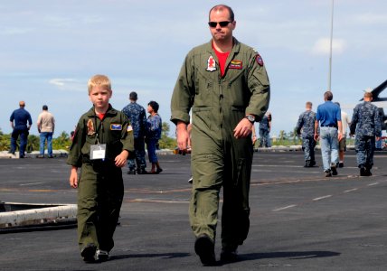US Navy 110610-N-GZ277-037 Lt. Todd Petrie, assigned to Strike Fighter Squadron (VFA) 22, walks with his sponsored tiger cruise participant on the