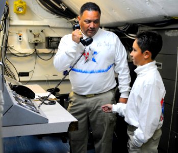 US Navy 110610-N-OK922-318 Chief Interior Communications Electrician Julio Salazar explains the equipment he works with to his sponsored tiger crui