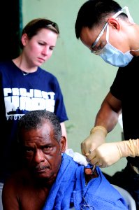US Navy 110609-N-EP471-097 Lt. Cmdr. Philip Letada emoves a melanoma from a Colombian patient's shoulder during a Continuing Promise 2011 community photo