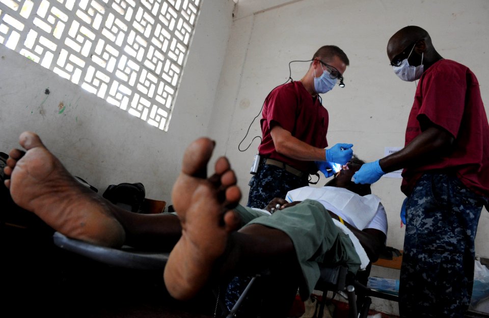 US Navy 110609-F-ET173-056 Lt. Joshua Fair and Hospital Corpsman 2nd Class Terrell Conley extract a patient's tooth